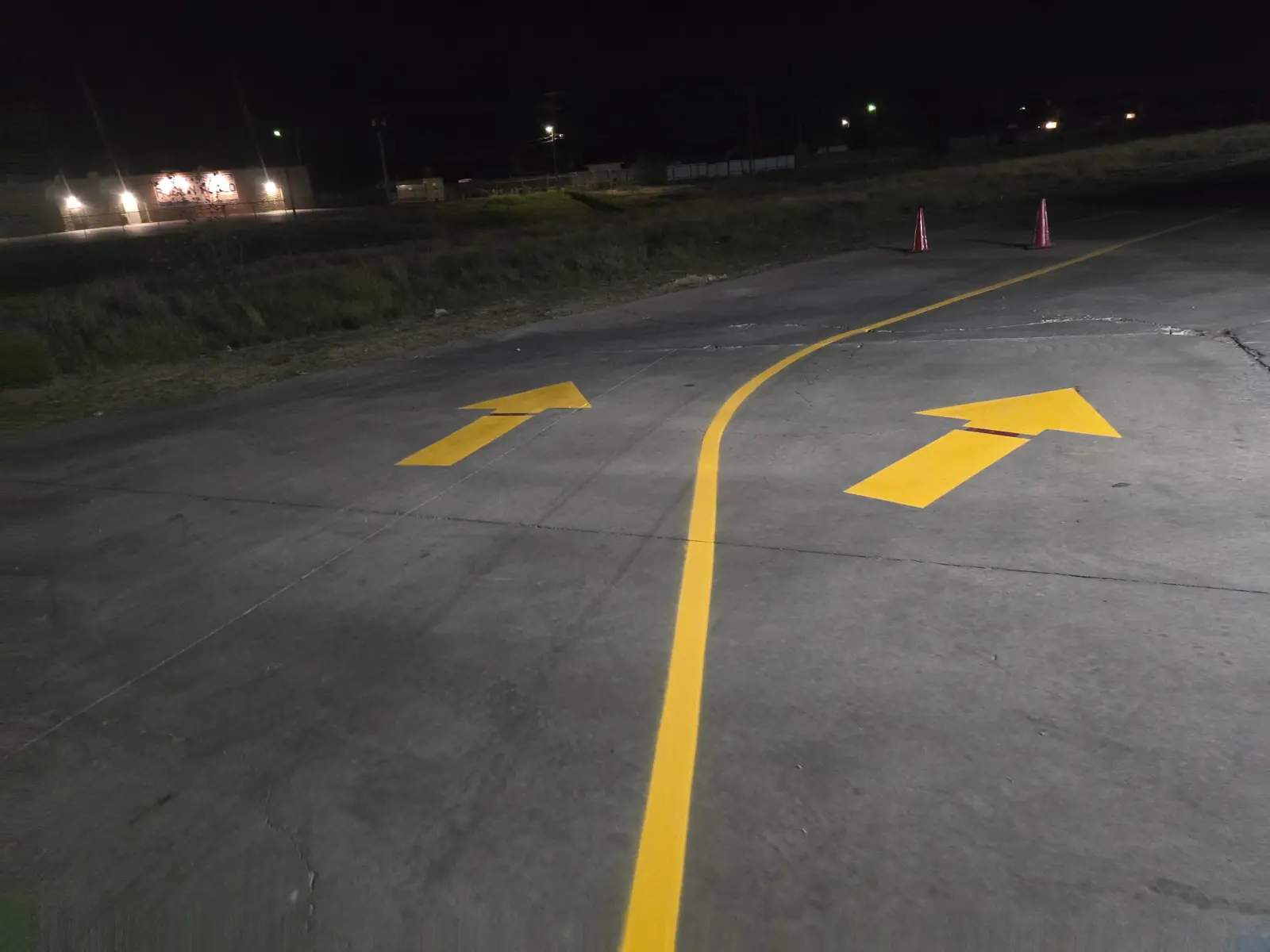 Yellow lane line and directional arrows on a parking lot at night