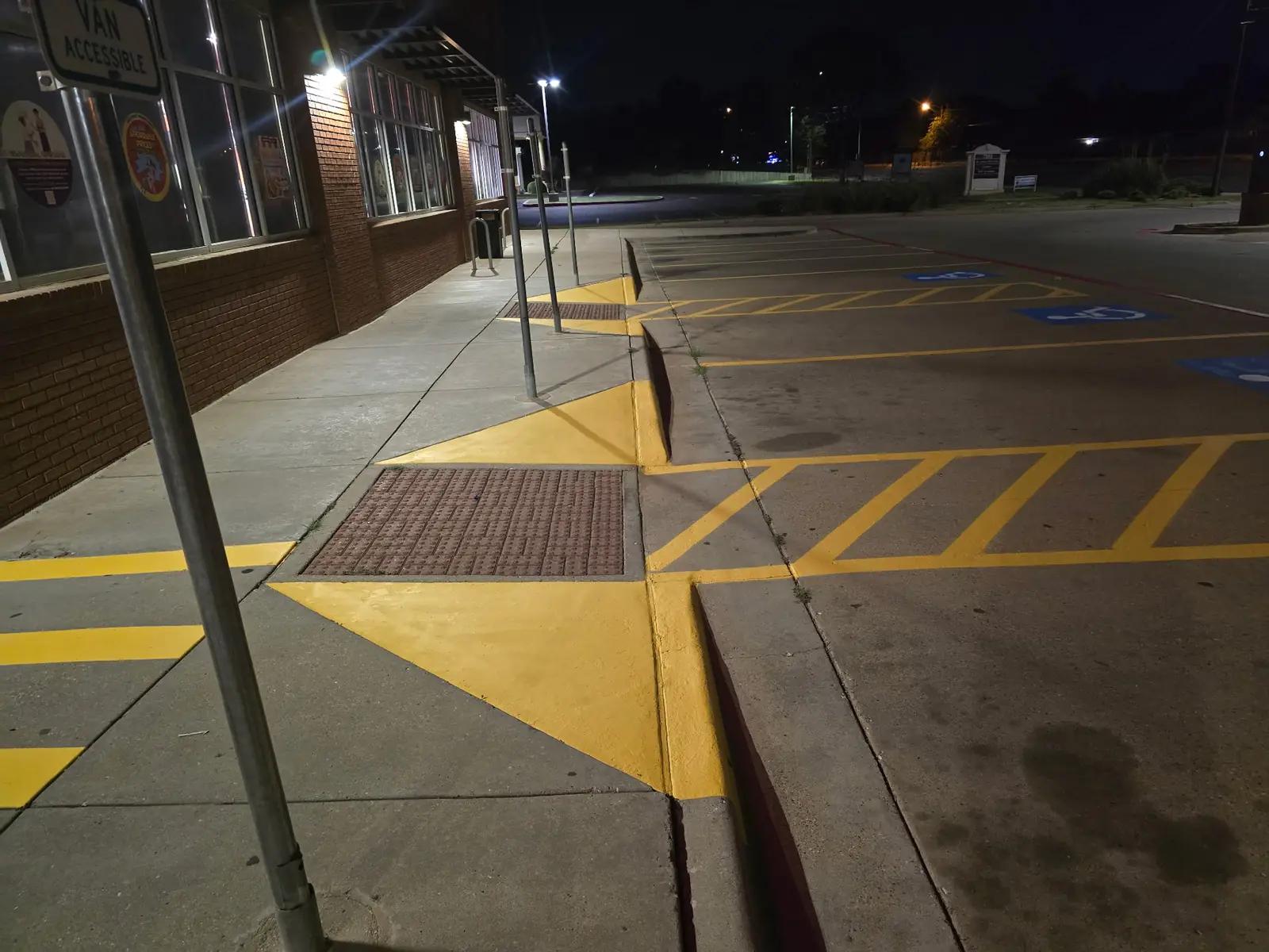 Yellow crosshatch and curb ramp markings along a storefront