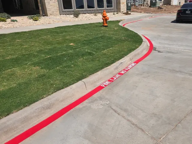 Red fire-lane curb curving around the lawn and hydrant